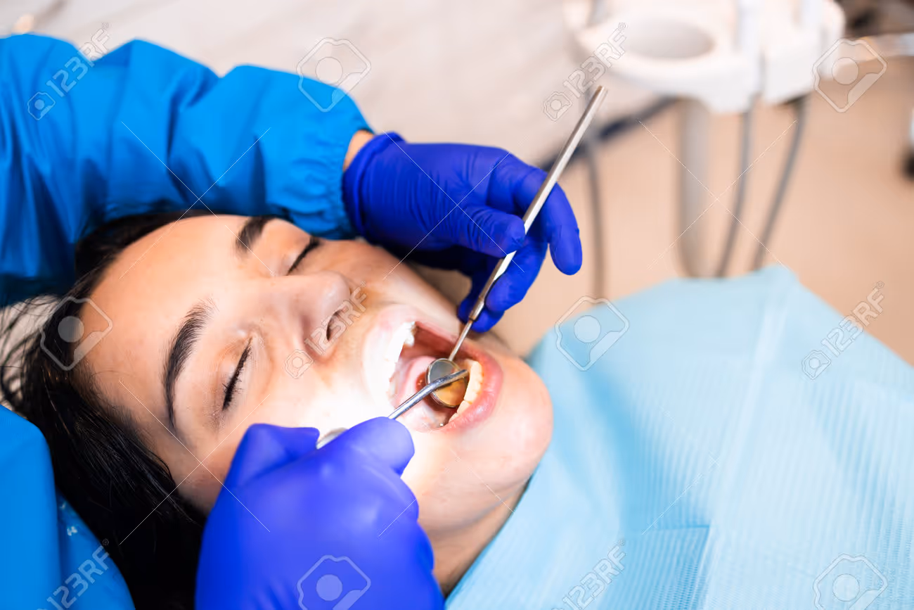 A female dentist wearing a mask and gloves uses a handheld intraoral scanner to create a digital impression of a male patient's teeth in a modern dental office.
