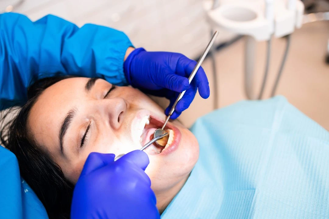 187069919_l A female dentist wearing a mask and gloves uses a handheld intraoral scanner to create a digital impression of a male patient's teeth in a modern dental office.